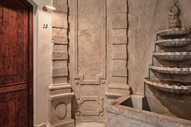 Hospes Palacio del Bailío - Fuente de mármol en cascada junto a un muro de piedra labrada y la puerta de una habitación